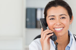 Picture of a female healthcare worker holding a phone up to her ear and smiling.